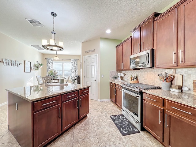 kitchen featuring hanging light fixtures, decorative backsplash, a kitchen island, light stone counters, and stainless steel appliances