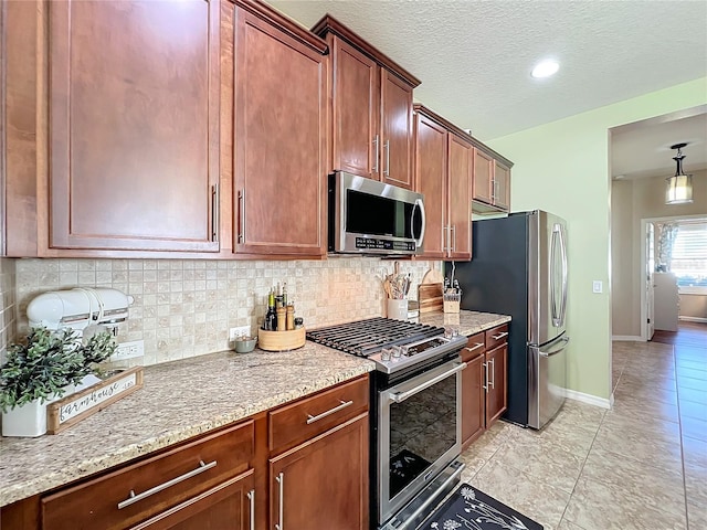 kitchen featuring light stone countertops, appliances with stainless steel finishes, decorative backsplash, and light tile patterned flooring