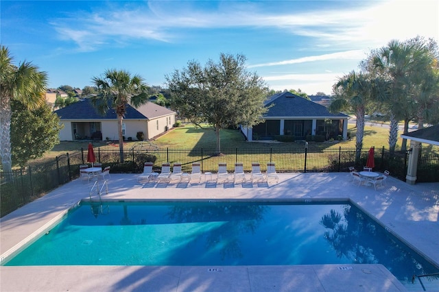 view of swimming pool with a sunroom, a patio area, and a lawn