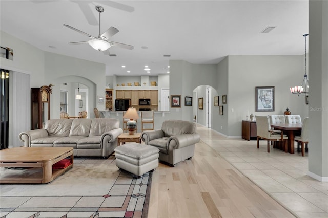 living room with light tile patterned floors and ceiling fan with notable chandelier