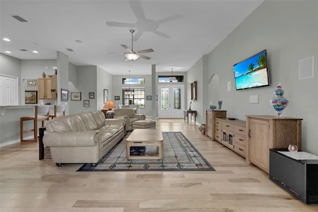 living room featuring ceiling fan, a towering ceiling, and light hardwood / wood-style flooring