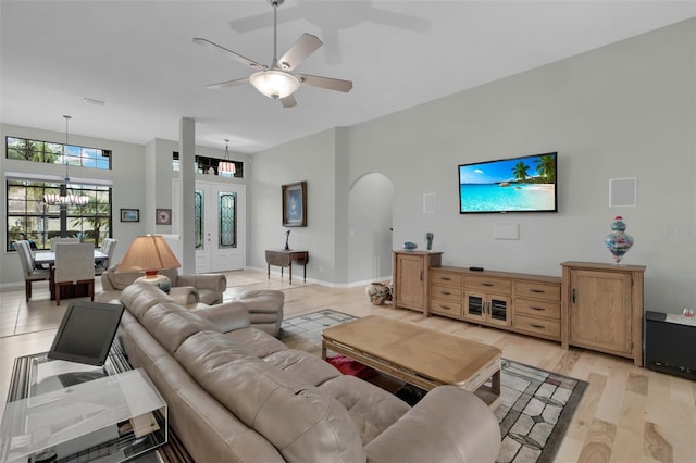 living room featuring ceiling fan with notable chandelier and light hardwood / wood-style floors