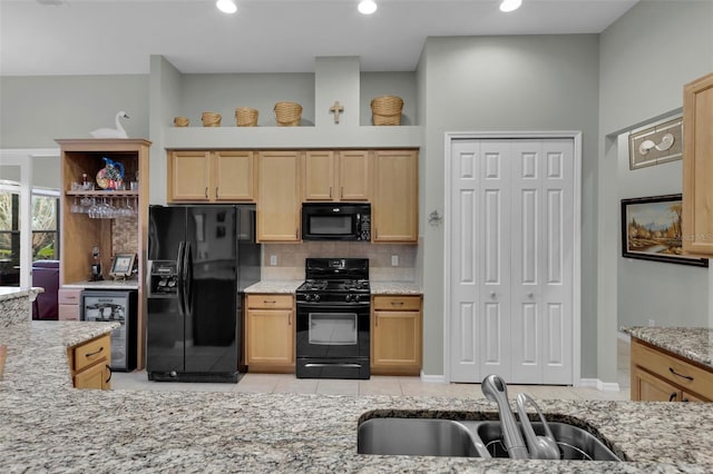 kitchen with sink, light stone counters, wine cooler, and black appliances