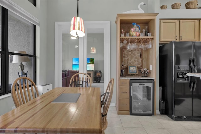 kitchen featuring black fridge, wine cooler, light tile patterned floors, light brown cabinetry, and decorative light fixtures