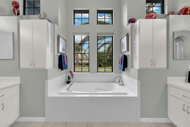 bathroom featuring a relaxing tiled tub, vanity, and a healthy amount of sunlight