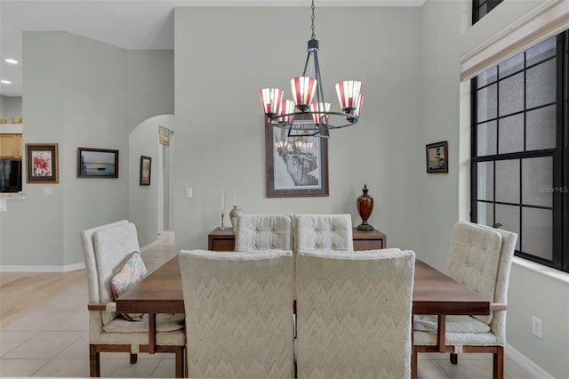 dining room with an inviting chandelier, light tile patterned floors, baseboards, and arched walkways