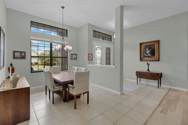 dining space with a notable chandelier, light tile patterned flooring, and baseboards