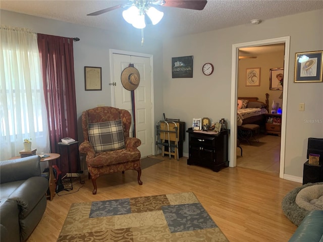 sitting room featuring a textured ceiling, light wood-type flooring, and ceiling fan