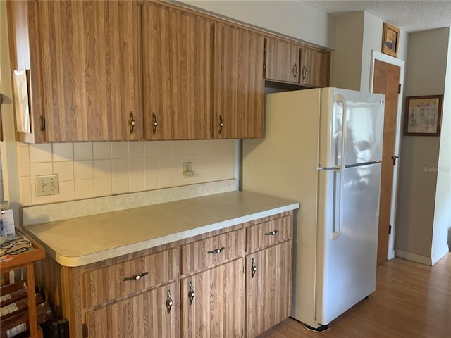 kitchen featuring backsplash, white fridge, and hardwood / wood-style flooring