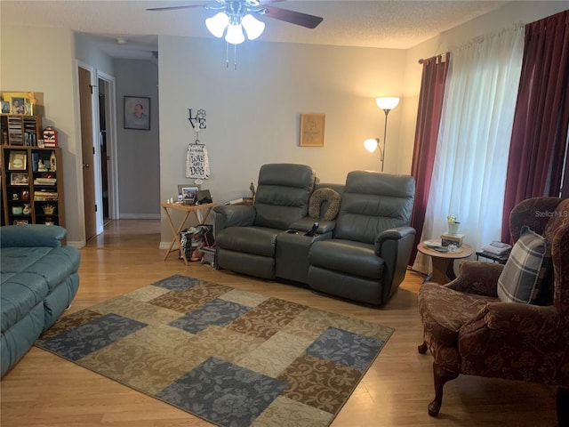 living room featuring a textured ceiling, light wood-type flooring, and ceiling fan