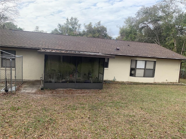 rear view of house with a sunroom and a lawn