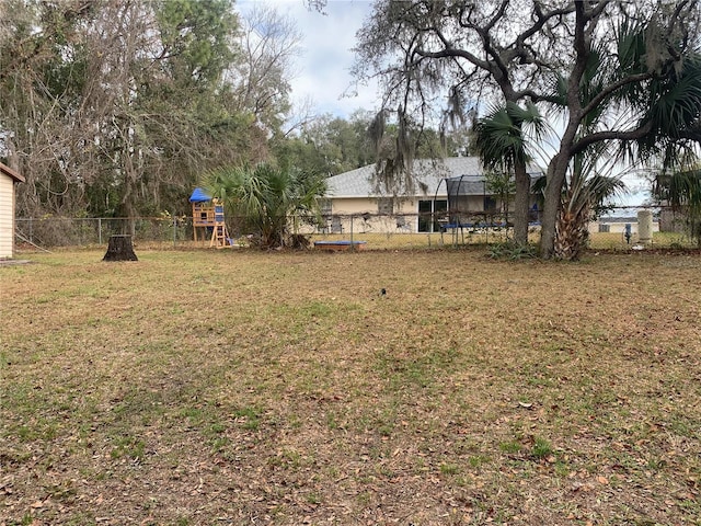 view of yard featuring a playground and a trampoline