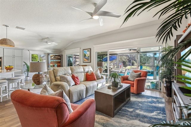 living room featuring vaulted ceiling, ornamental molding, ceiling fan, and plenty of natural light