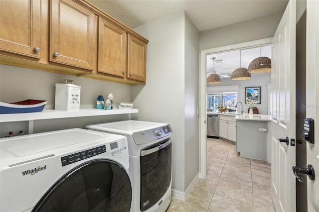 laundry room featuring separate washer and dryer, sink, cabinets, light tile patterned floors, and a textured ceiling