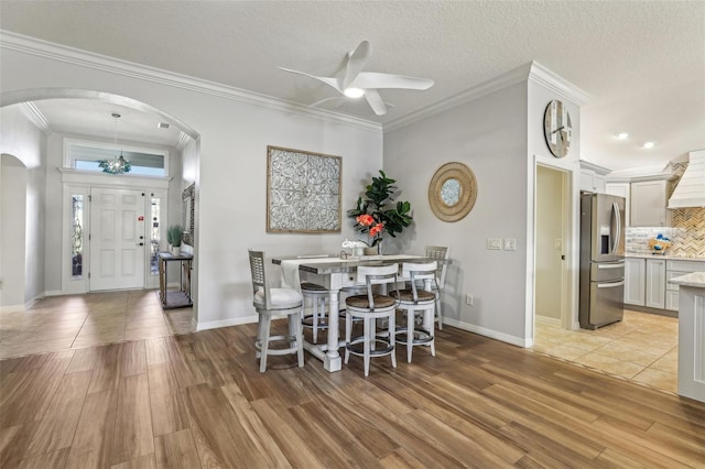 dining area with crown molding, ceiling fan, light hardwood / wood-style floors, and a textured ceiling