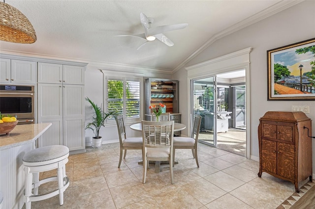 dining space featuring vaulted ceiling, a textured ceiling, light tile patterned floors, ornamental molding, and ceiling fan