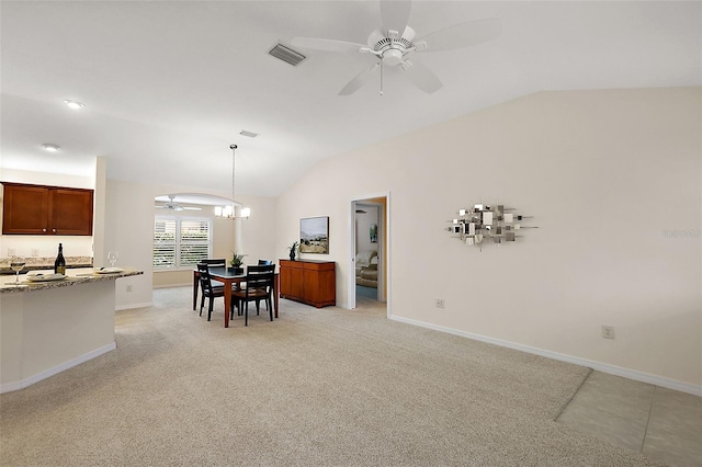 dining space with ceiling fan with notable chandelier, vaulted ceiling, and light colored carpet