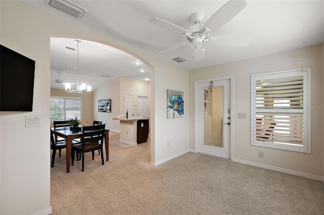 carpeted dining area with lofted ceiling and ceiling fan with notable chandelier