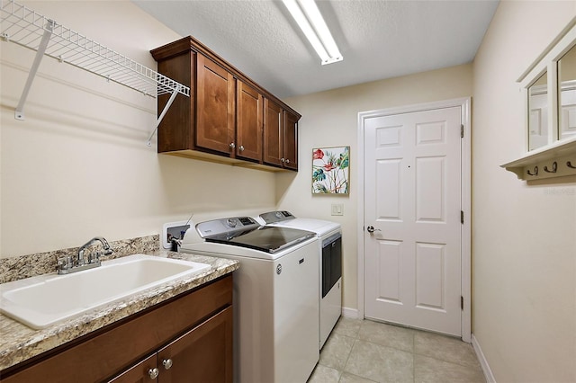 laundry room with sink, a textured ceiling, cabinets, light tile patterned floors, and washer and dryer