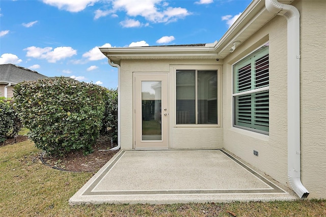 view of exterior entry featuring a yard and a patio area