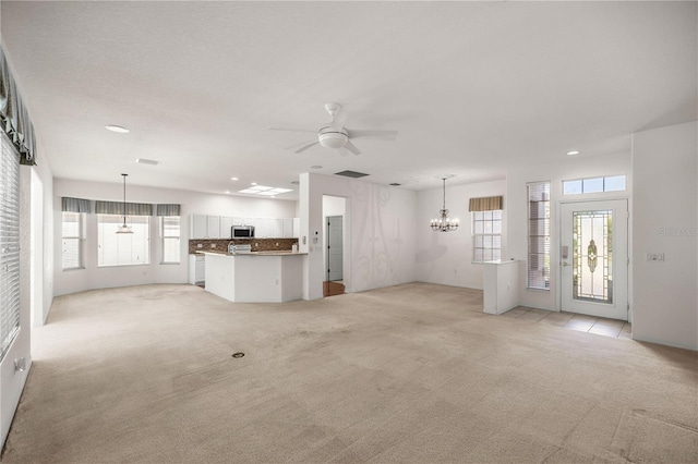 unfurnished living room featuring light colored carpet and ceiling fan with notable chandelier