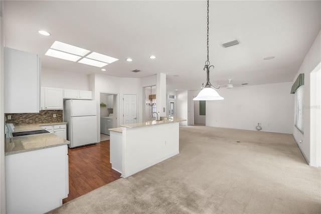 kitchen featuring white fridge, a center island, hanging light fixtures, white cabinets, and sink