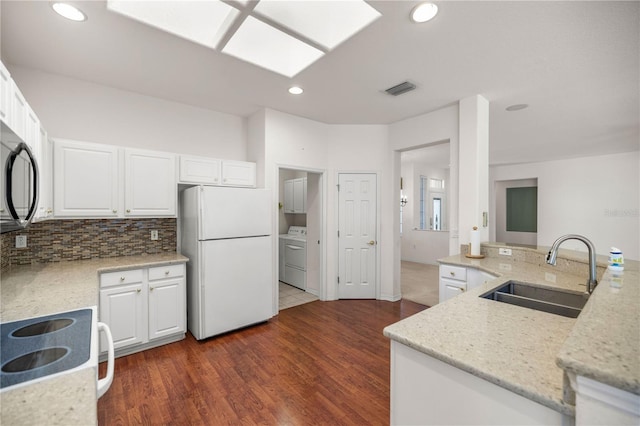 kitchen with white cabinets, sink, light stone counters, and white fridge