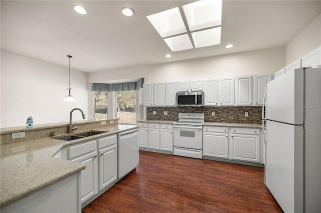 kitchen with a skylight, sink, white appliances, and white cabinetry