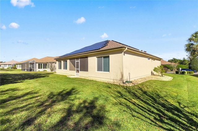 back of house featuring a lawn and solar panels