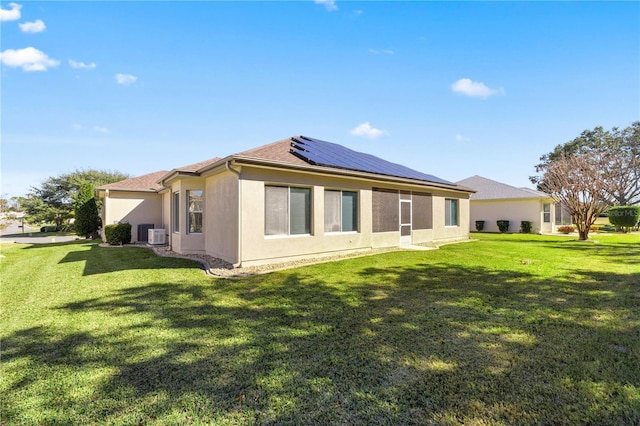 back of property with solar panels and a yard