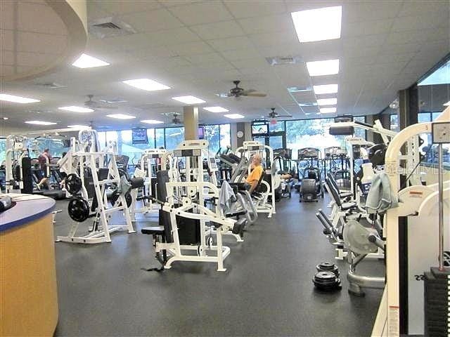 workout area with ceiling fan, a wall of windows, and a paneled ceiling