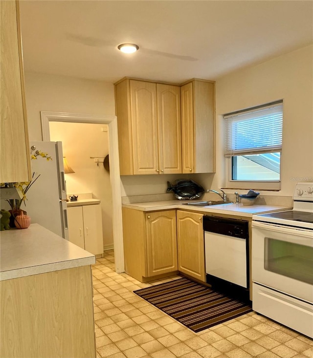 kitchen with light brown cabinets, white appliances, and sink