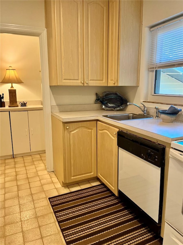 kitchen with light brown cabinets, white dishwasher, and sink