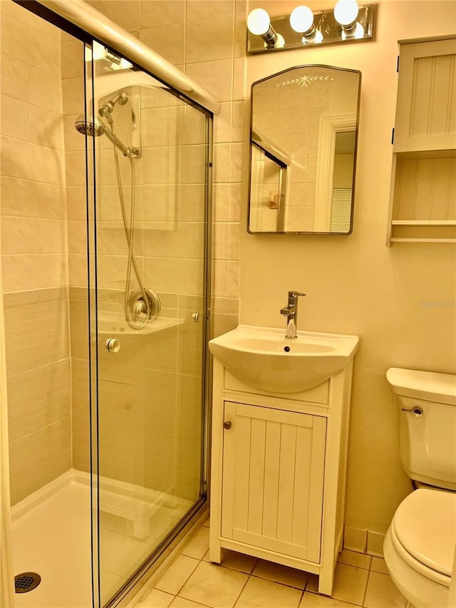 bathroom with tile patterned flooring, vanity, toilet, and walk in shower