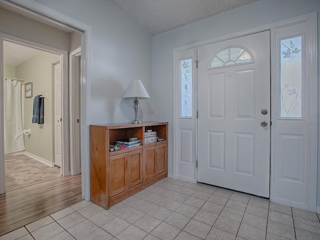 foyer entrance with a textured ceiling and light tile patterned flooring