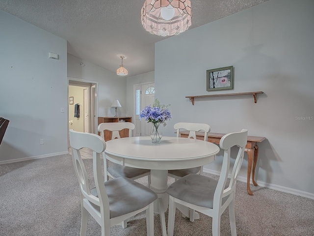 dining room featuring vaulted ceiling, light carpet, and a textured ceiling