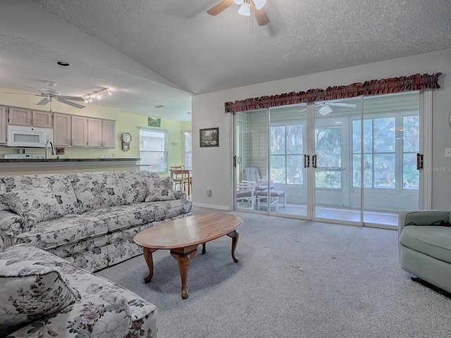 living room featuring ceiling fan, light colored carpet, a textured ceiling, and vaulted ceiling