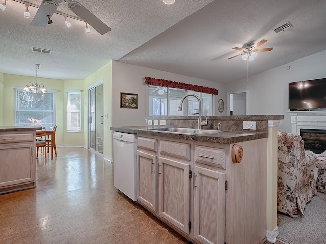 kitchen featuring light brown cabinetry, white dishwasher, sink, hanging light fixtures, and an island with sink