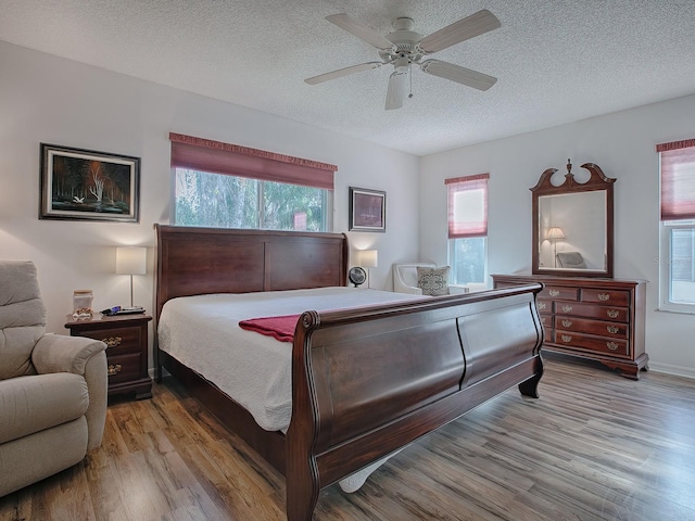 bedroom with ceiling fan, light hardwood / wood-style floors, and a textured ceiling