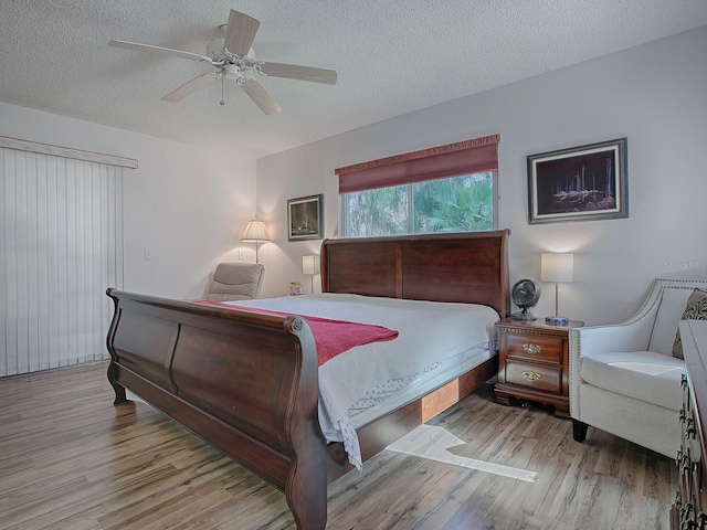 bedroom featuring ceiling fan, light hardwood / wood-style floors, and a textured ceiling