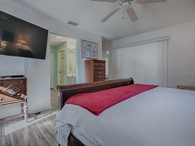 bedroom featuring a textured ceiling, ceiling fan, light wood-type flooring, and ensuite bathroom