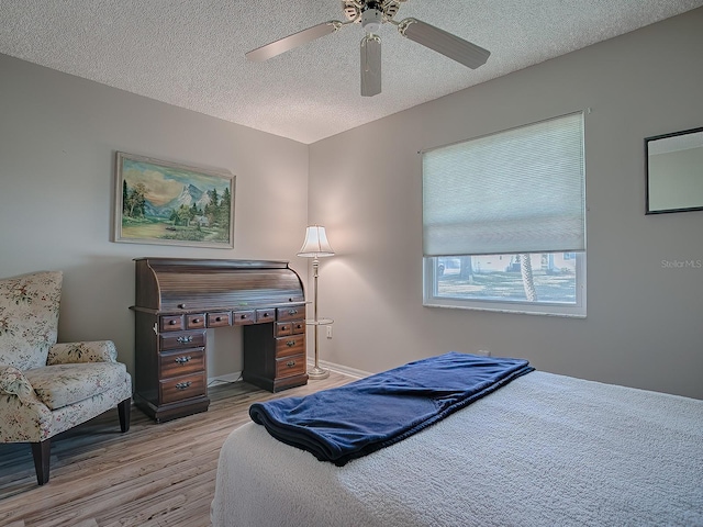 bedroom featuring ceiling fan, light hardwood / wood-style floors, and a textured ceiling