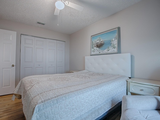 bedroom featuring dark hardwood / wood-style flooring, a textured ceiling, a closet, and ceiling fan