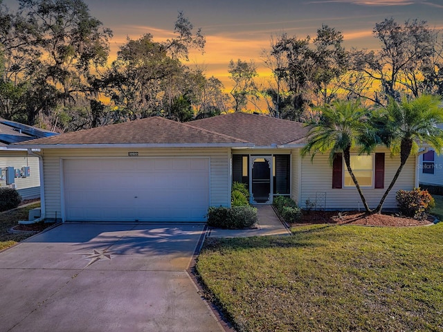 single story home featuring a garage and a lawn