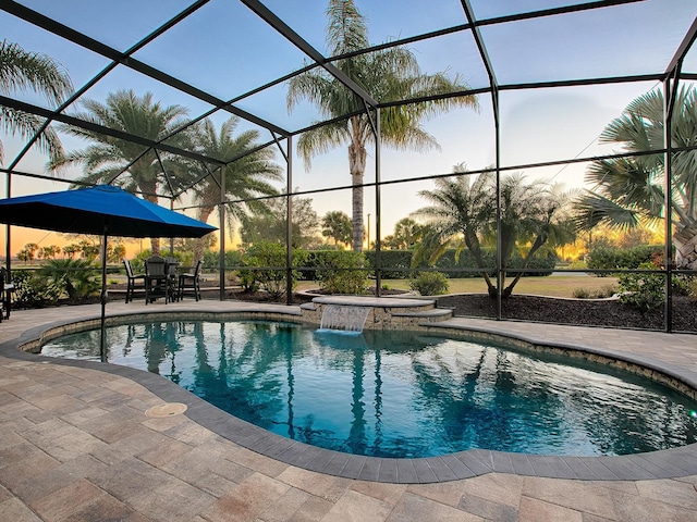 pool at dusk featuring a patio area and a lanai