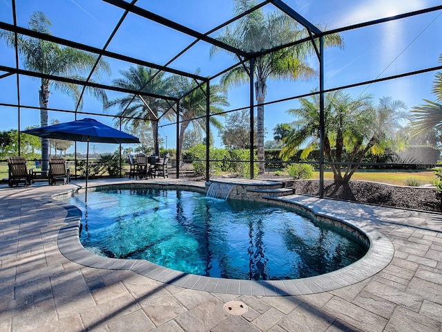 view of pool featuring glass enclosure, an in ground hot tub, pool water feature, and a patio