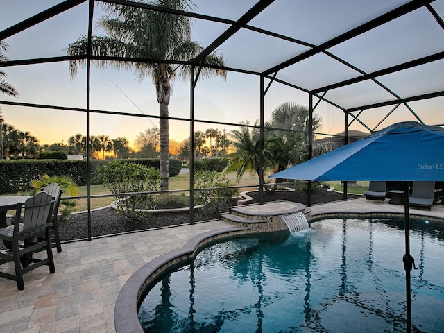 pool at dusk featuring pool water feature, a lanai, and a patio