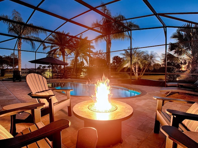 patio terrace at dusk with glass enclosure and an outdoor fire pit