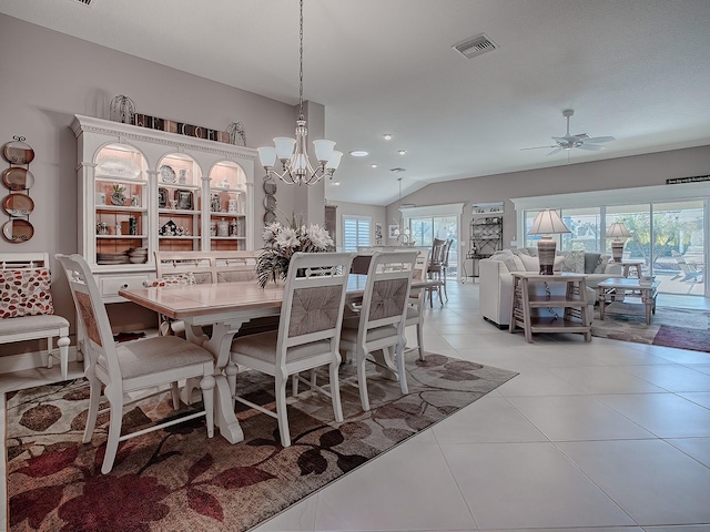 tiled dining space with ceiling fan with notable chandelier and lofted ceiling