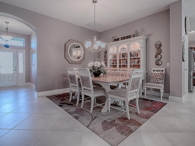 dining area featuring light tile patterned flooring, a textured ceiling, and an inviting chandelier